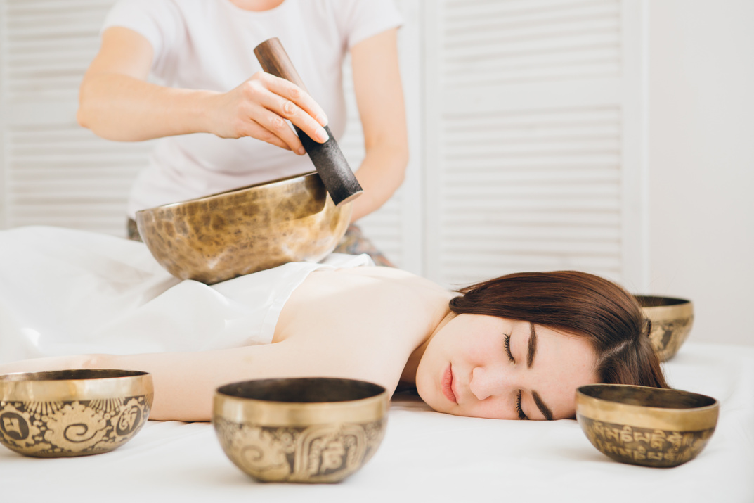 Girl doing massage therapy singing bowls in the Spa